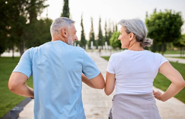 фото со спины активной зрелой пары, улыбающейся во время пробежки до - physical activity стоковые фото и изображения