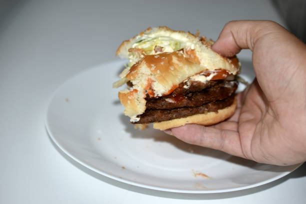 istock Double meat burger in hand on a white background 1339839478