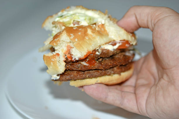 istock Double meat burger in hand on a white background 1339839568