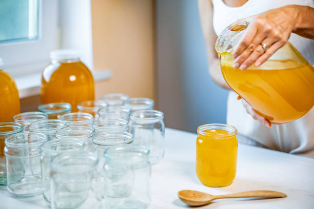 istock Woman pours honey into transparent jars on a white table 1339842965