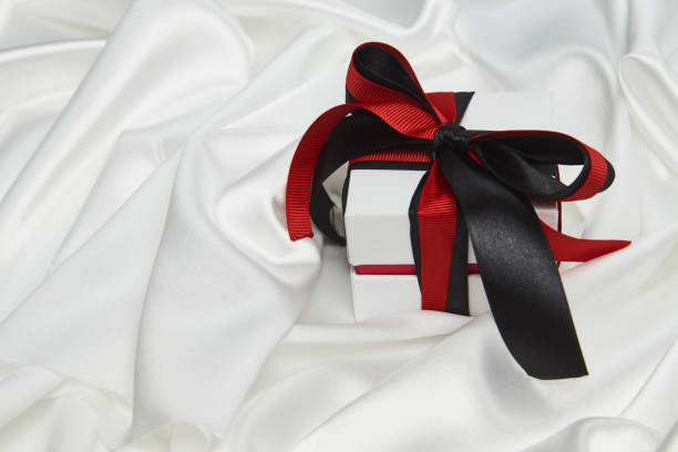 istock Christmas gift box with ribbon on white silk background 1339844480