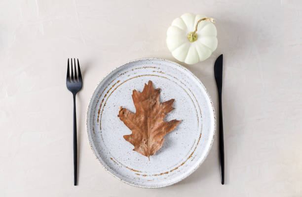 istock Autumn table setting, plate, appliances and pumpkin on a beige background 1339844672