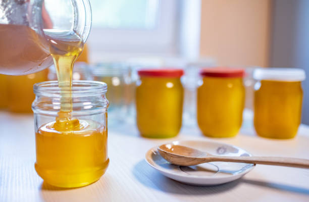 istock Someone pours honey into transparent jars on a white table 1339844732
