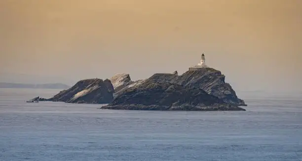 Photo of View of Unst Island, the northernmost of the Shetland Islands, Scotland with its lighthouse and huge bird colonies. The bird guano making the cliffs  almost entirely white