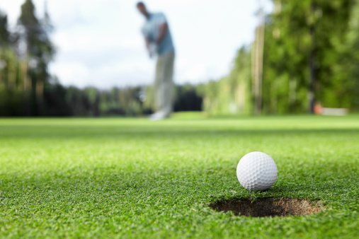 The golf ball is right in front of the hole.The score is guaranteed. Large copy space on green grass. 3D rendered objects and clear, simple design.