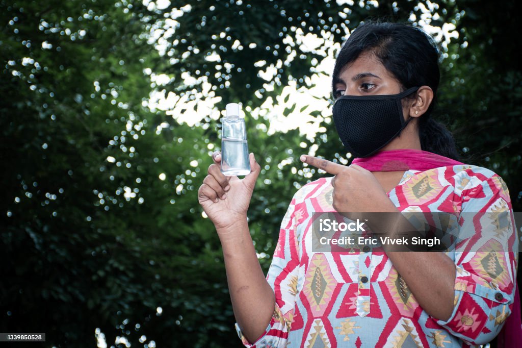 woman showing at sanitizer outdoor with black mask corona virus Outdoor picture of a woman showing at sanitizer 20-29 Years Stock Photo