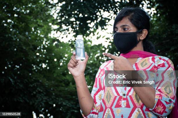 Woman Showing At Sanitizer Outdoor With Black Mask Corona Virus Stock Photo - Download Image Now