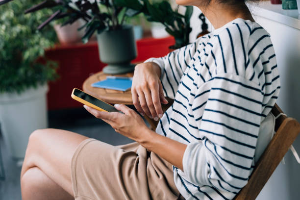 istock Unrecognizable Woman Sitting on her Balcony Surrounded by Potted Plants and Using her Smartphone 1339854979