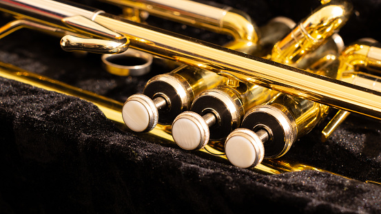 Close-up pearl keys on golden brass Trumpet in a black velvet case. Selective focus