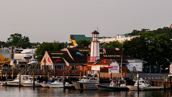 Norwalk, CT, USA - September 12, 2021: Waterside dinning restaurant with beautiful sunrise light and boats docking in Norwalk river near downtown