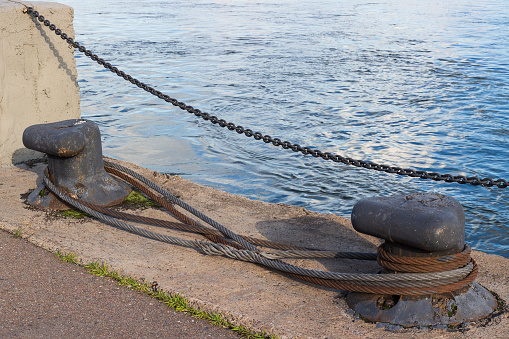Two bollard with metal ropes on a pier. Mooring bitt on the wharf.