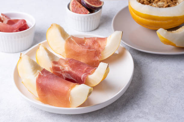istock Plate with italian ham and melon slices, prosciutto with fruit, jamon on a white background. 1339861533