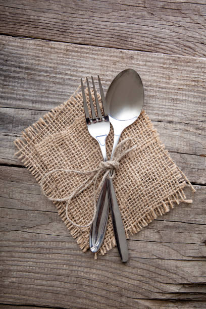 istock Fork and Spoon on old wooden table napkin and burlap, grunge rustic style, top view. 1339861881