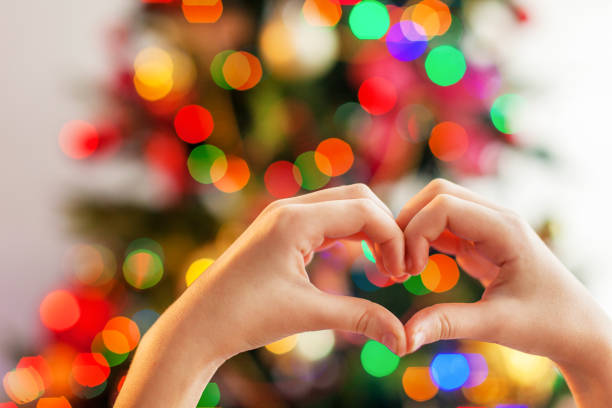 istock Heart from the hands in front of  christmas tree 1339864239