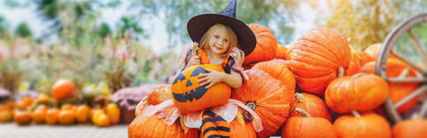 kind mädchen als kleine süße hexe mit kürbis draußen in halloween - pumpkin child little girls pumpkin patch stock-fotos und bilder