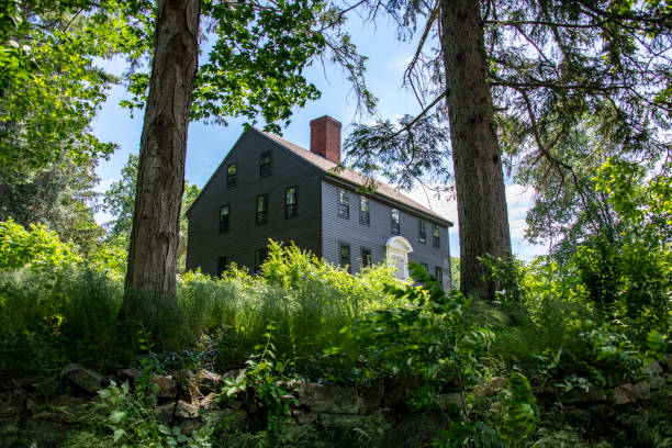 Ramsey, New Jersey, USA - May 12th, 2025: A large home is surrounded with dense towering Evergreen trees between it and the neighboring house.