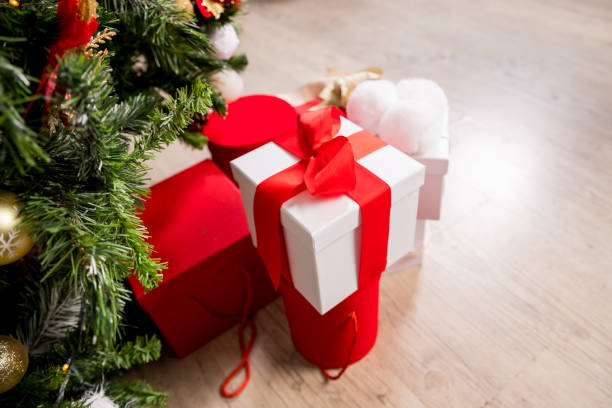 istock Different Christmas presents with handmade decoration.Wrapped in red paper present boxes under christmas tree. New year tree with ornaments and garland. Winter holiday background.many gifts. 1339884987