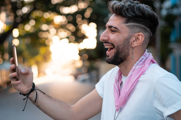 Smiling gay man takes selfie Smiling gay man takes selfie in the city half shaved hairstyle stock pictures, royalty-free photos & images