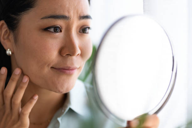 istock Young Asian woman looking herself in the mirror. 1339891467