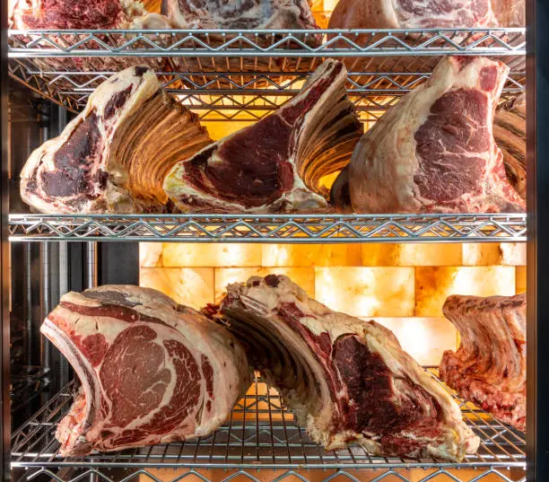 Beef steak in dry aged meat aging cabinet. Barbecue steak on fridge in delicious gourmet restaurant. Dry aging meat in cold storage. Dry-aged cuts of raw meat, aged beef for steaks