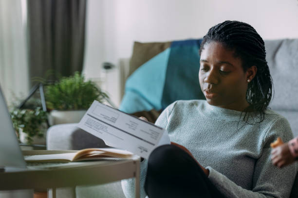 istock Women in Business: A Young Woman Reading a Utility Bill while Working from Home 1339901454