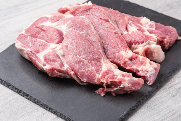 istock Several sliced steaks of pork neck on black stone board on gray kitchen table. Close up view. 1339902241