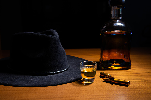 distribution of a hat whiskey on a wooden table with bullets.