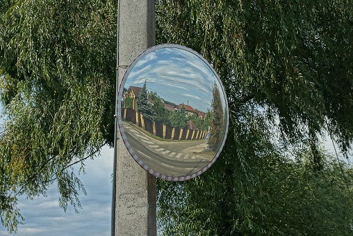 one large round observation mirror on a concrete pillar outside in green vegetation