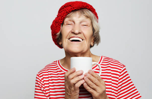 old excited lady smiling laughing, holding cup drinking coffee