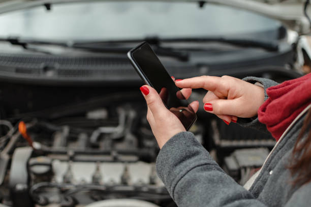 istock Hands of a young latina using her cell phone on her broken car engine 1339921638