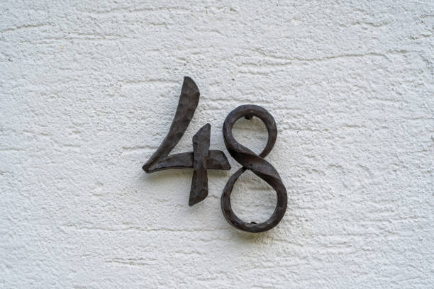 istock Metal house number 48 on a white stucco wall background 1339934574
