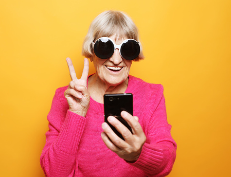 Elderly lady holding a smartphone and making v-sign