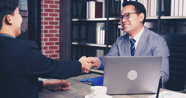 Success collaboration partners sign contract and shake hands after success business joint venture deal. Diversity Businessman shake hands together in a meeting. Trustworthy meeting business concept. stock photo
