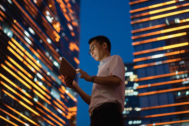 Man using tablet in central business district at night