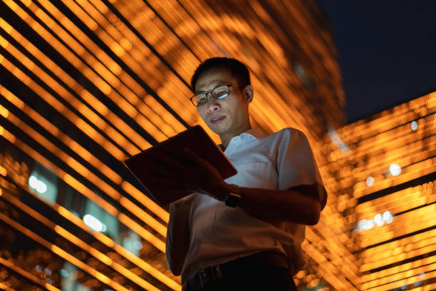 istock Man using tablet in central business district at night 1339958186