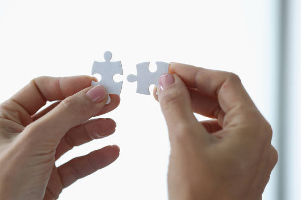 istock Female hands holding two white puzzle pieces closeup 1339960317