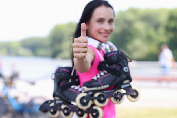 Smiling woman with rollers on shoulder showing thumb up closeup. Sale of sporting goods concept