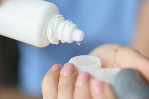 istock Woman pouring lens solution from bottle into plastic container closeup 1339960357