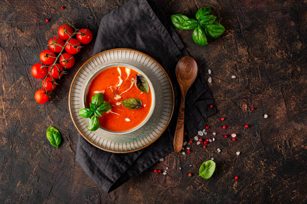 eine schüssel traditionelle spanische tomatensuppe mit sahne und basilikum auf dem dunklen hintergrund dreschansicht. tomaten-basilikum-gazpacho in einer grauen schüssel - tomatensuppe stock-fotos und bilder