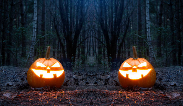 istock Scary glowing halloween pumpkins in the night forest. 1339965968
