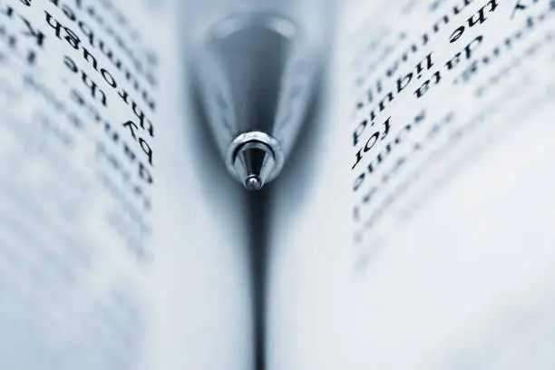Photo of A blue ball pen embedded in an open book