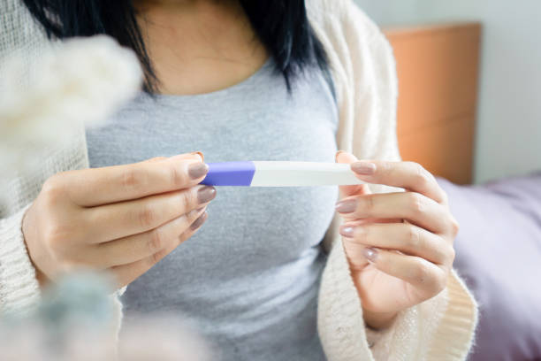 frau, die einen schwangerschaftstest hält, der das positive, negative ergebnis betrachtet - pregnancy test human pregnancy medical test human fertility stock-fotos und bilder