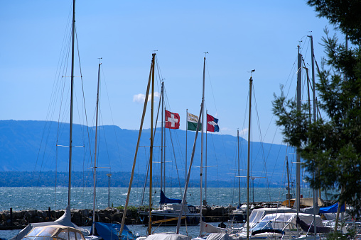 Flags blowing in the wind at harbor of City of Nyon on a cloud summer day. Photo taken August 28th, 2021, Nyon, Switzerland.