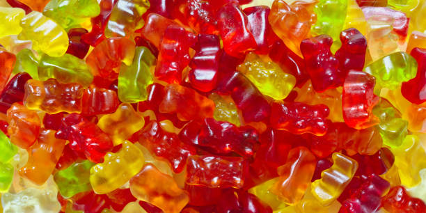 background from gummy bears. multi-colored chewy candies, vitamins, close-up. top view. - multi vitamine stockfoto's en -beelden