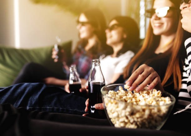 un groupe de personnes regarde un film. les filles amies mangent du maïs soufflé et boivent du soda - friends television show photos et images de collection