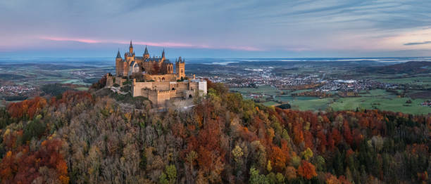 Hohenzollern Castle in Autumn Sunrise Panorama Burg Hohenzollern Castle Germany Bisingen, Baden Württemberg, Germany - October, 25th 2020: Swabian Jura Germany Autumn Aerial Panorama with Hohenzollern Castle - Burg Hohenzollern 15th century hilltop castle in sunrise light in autumn season. Colorful surrounding autumn colored trees around the hill of Burg Hohenzollern, view to the surrounding cities of Hechingen, Bisingen and Tübingen on the horizon. Aerial Drone Point of view stiched XXXL Panorama. Swabian Jura, Baden Württemberg, Southwest Germany, Germany, Europe. reutlingen stock pictures, royalty-free photos & images