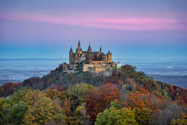 Sunrise over Hohenzollern Castle in Autumn Burg Hohenzollern Castle Germany Bisingen, Baden Württemberg, Germany - October, 25th 2020: Swabian Jura Germany Autumn Aerial Panorama with Hohenzollern Castle - Burg Hohenzollern 15th century hilltop castle in sunrise light in autumn season. Colorful surrounding autumn colored trees around the hill of Burg Hohenzollern, view to the surrounding cities of Hechingen, Bisingen and Tübingen on the horizon. Aerial Drone Point of view stiched XXXL Panorama. Swabian Jura, Baden Württemberg, Southwest Germany, Germany, Europe. reutlingen stock pictures, royalty-free photos & images