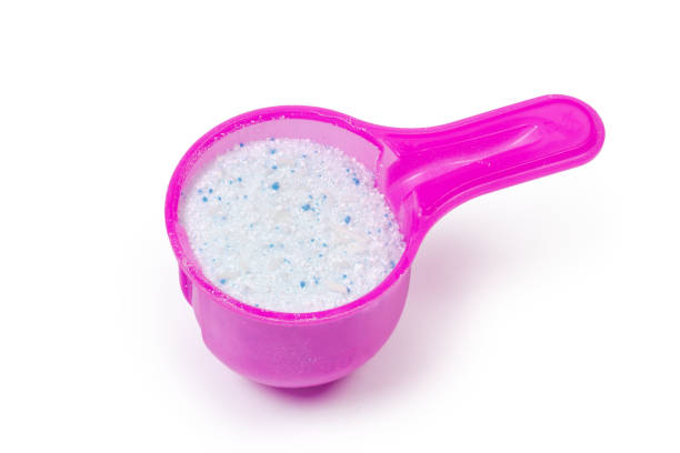 White powdered laundry detergent in plastic measuring scoop on a white background
