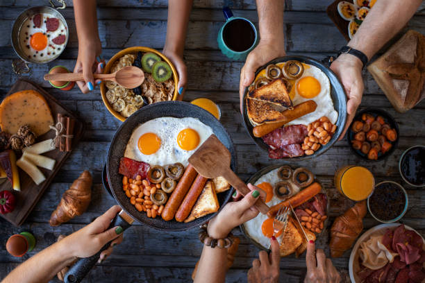 vista ravvicinata del tavolo della colazione con la famiglia. - breakfast eggs fried egg sausage foto e immagini stock