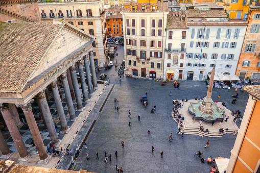 A suggestive view over the roofs and terraces of Rome from the top of the Roman Pantheon, in the Rione Pigna (Pigna District), in the historic heart of the Eternal City. To the left, in the Piazza della Rotonda, or Piazza del Pantheon, the Baroque fountain and Egyptian obelisk designed in 1575 by Giacomo della Porta. Built in 27 BC by the Consul Marco Vispanio Agrippa for the emperor Augustus and dedicated to all the Roman divinities, the majestic Pantheon is one of the best preserved Roman structures in the world. Currently owned by the Italian state, this Roman temple preserves the remains of some Italian royalty and the Renaissance painter Raphael. In 1980 the historic center of Rome was declared a World Heritage Site by Unesco. Image in high definition format.
